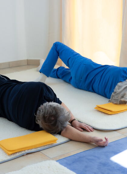 Zwei Frauen rollen am Boden auf die Rechte Seite, der rechte Arm ist gestreckt und sie rollen mit dem Kopf auf den rechten Arm.