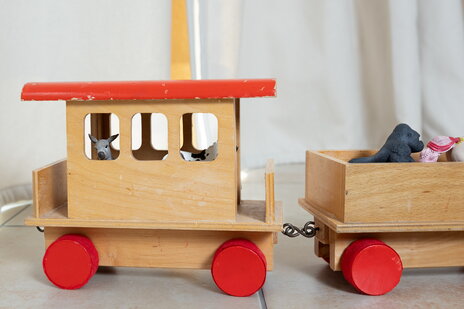 Waggon einer Holzeisenbahn aus der ein Esel aus dem Fenster guckt